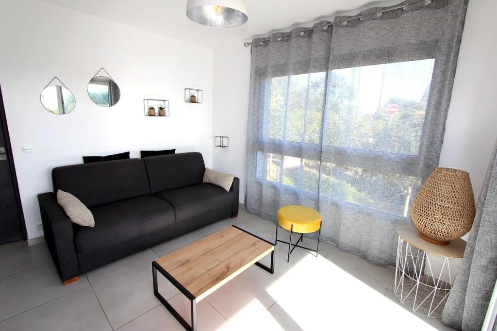 un salon avec un canapé noir et une table dans l'établissement T2 centre-ville de Porto-Vecchio, à Porto-Vecchio