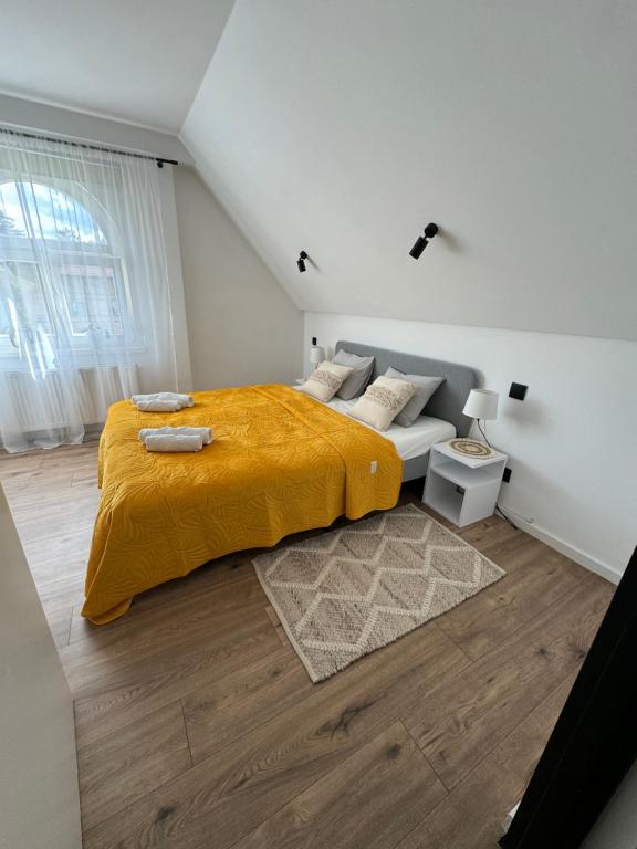 a bedroom with a bed with a yellow blanket at Apartamenty Astor - Słoneczny in Szczawno-Zdrój