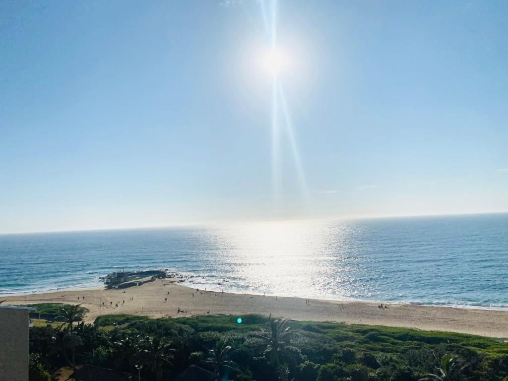 widok na plażę ze słońcem odbijającym się na wodzie w obiekcie Beach Front Holiday Apartment, Stella Maris, Beach Road, Amanzimtoti w mieście Amanzimtoti