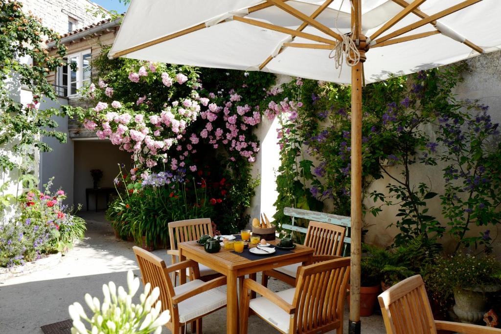a table and chairs under an umbrella on a patio at Hôtel Le Sénéchal in Ars-en-Ré