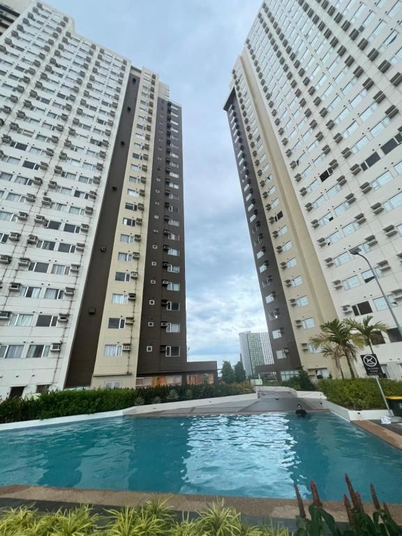 dos edificios altos con una piscina frente a ellos en Cozy Studio in Ayala Avida CDO - Fast WIFINetflixTv, en Cagayan de Oro