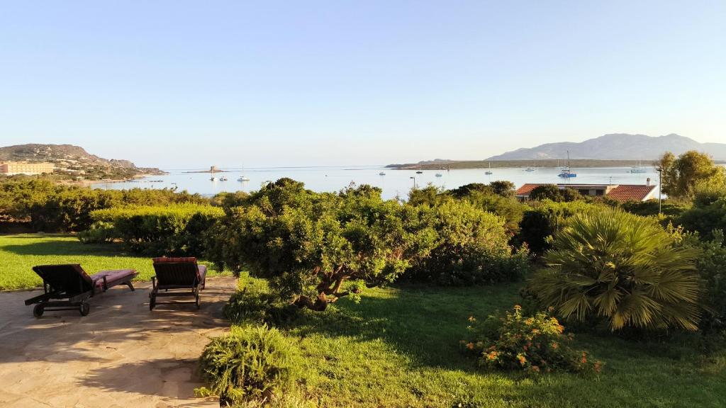 a garden with chairs and a view of the water at Villa Gino in Stintino