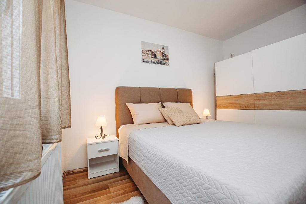 sypialnia z dużym łóżkiem z białą pościelą i drewnianą podłogą w obiekcie Apartman Ivana w mieście Zadar