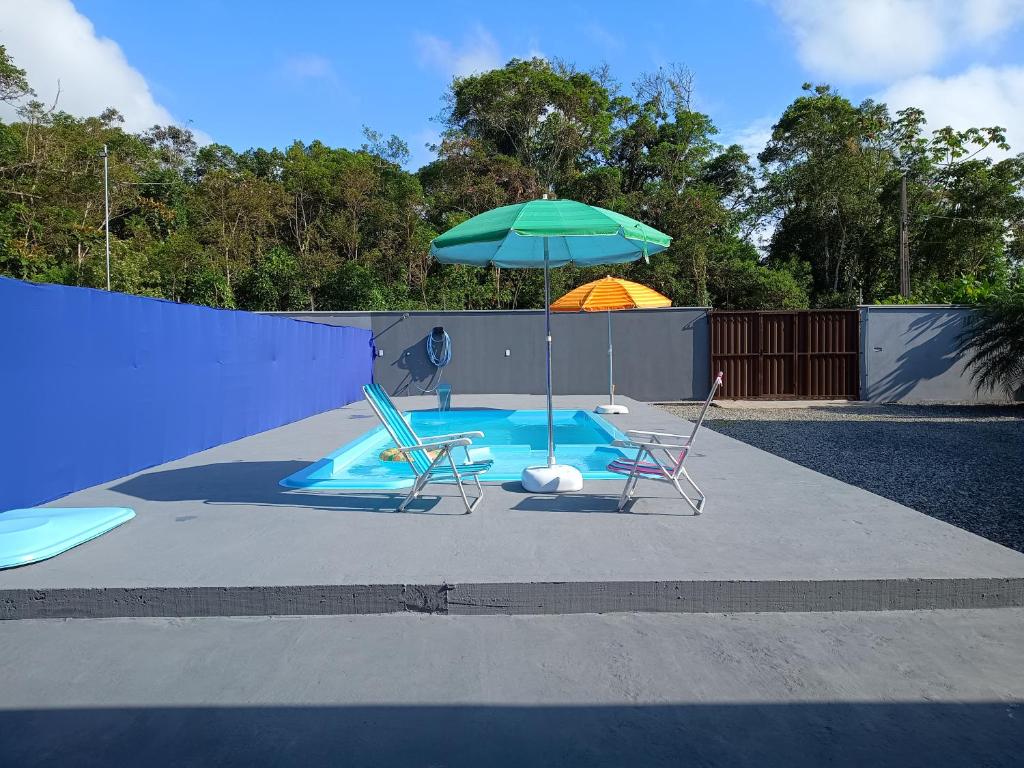 a swimming pool with two chairs and an umbrella at Casa com Piscina e ampla area de festas in Barra Velha