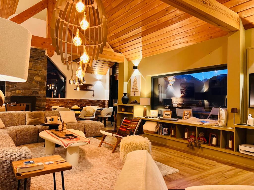Una sala de estar con un sofá y un televisor grande. en Chalet de luxe contemporain vue 360 degrés sur les montagnes, en Guchan