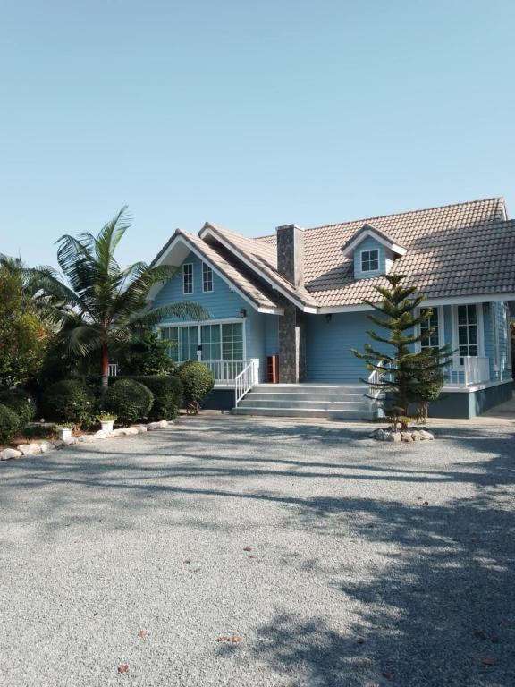 a blue house with a palm tree in the driveway at Baan Fah Chiangrai in Chiang Rai