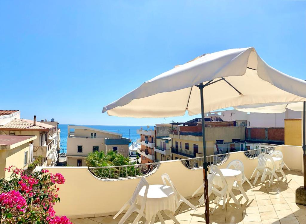 a patio with an umbrella and chairs and the ocean at Hotel Sylesia in Letojanni