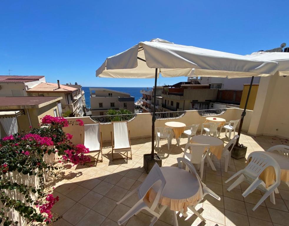 a patio with tables and chairs and an umbrella at Hotel Sylesia in Letojanni