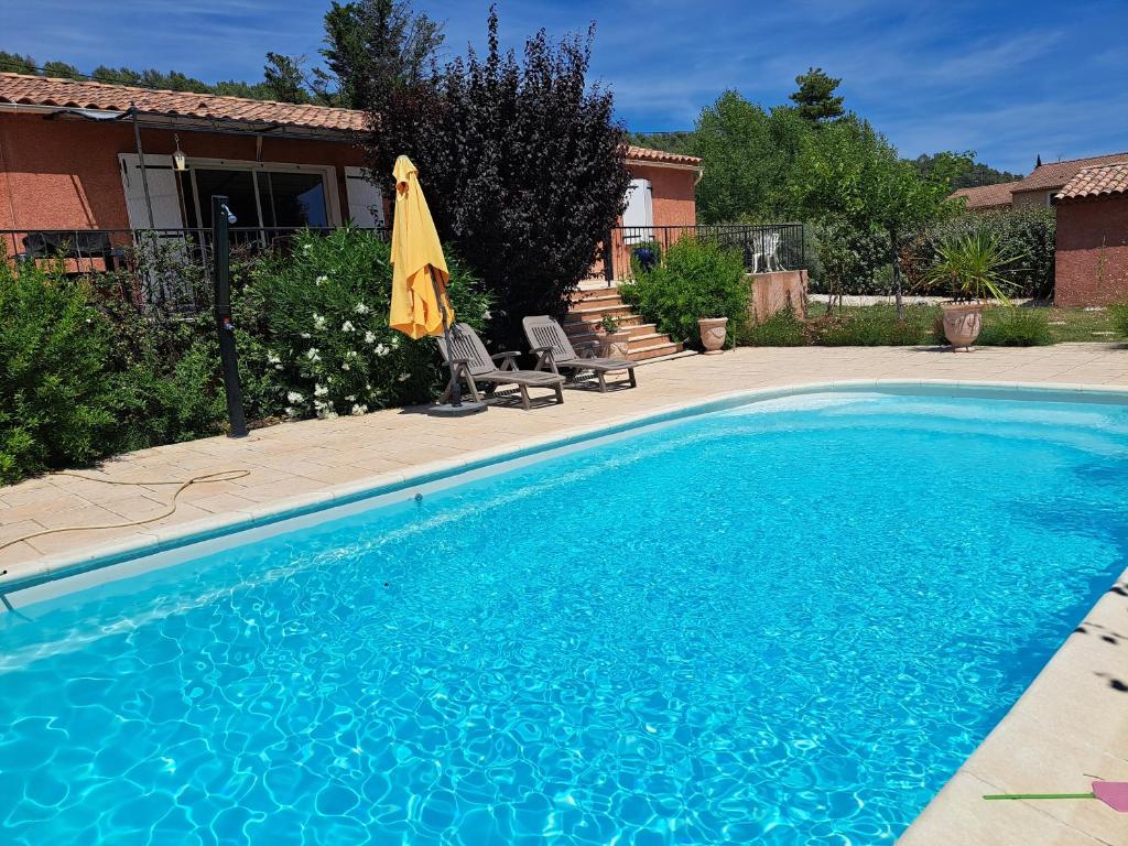 - une piscine bleue avec un parasol et des chaises dans l'établissement Maison en Provence verte classée 3 étoiles, à Camps-la-Source