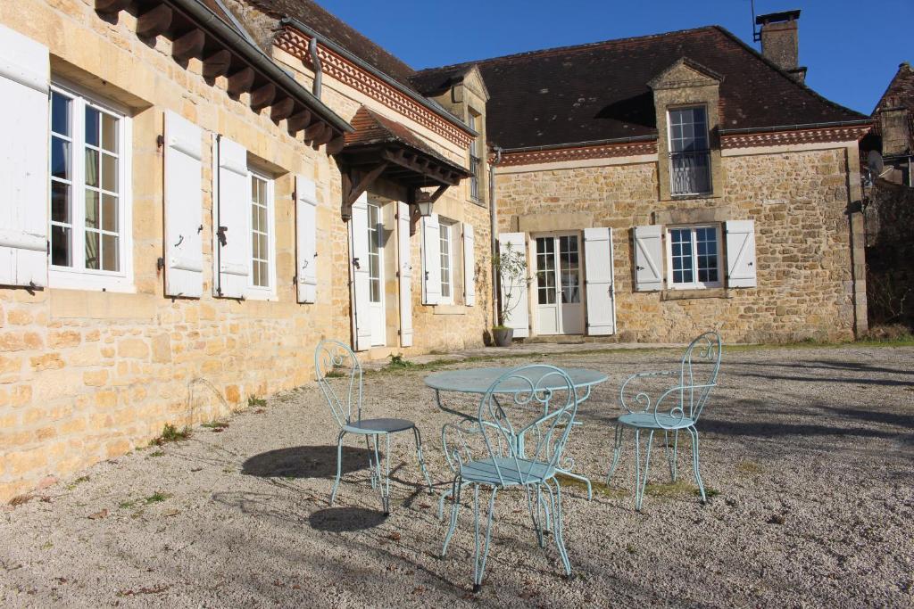 une table et des chaises devant un bâtiment dans l'établissement La Belle Mondane, en Dordogne, à Sainte-Mondane