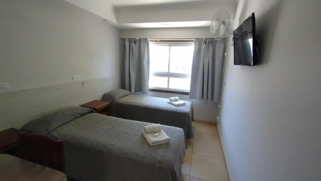 a room with two beds and a tv and a couch at Hotel Bertiami in Mar del Plata