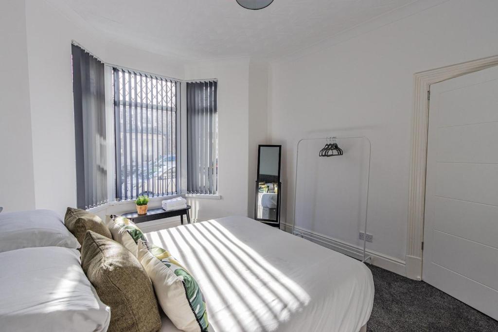 a white bedroom with a large bed and a window at The Luxury Home Free Parking 10 Min Walk to Cardiff Town in Cardiff