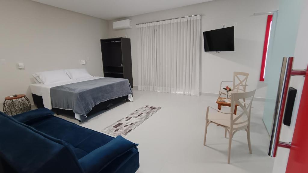 a living room with a bed and a blue couch at Suítes Nossa Senhora de Fátima in Pirenópolis