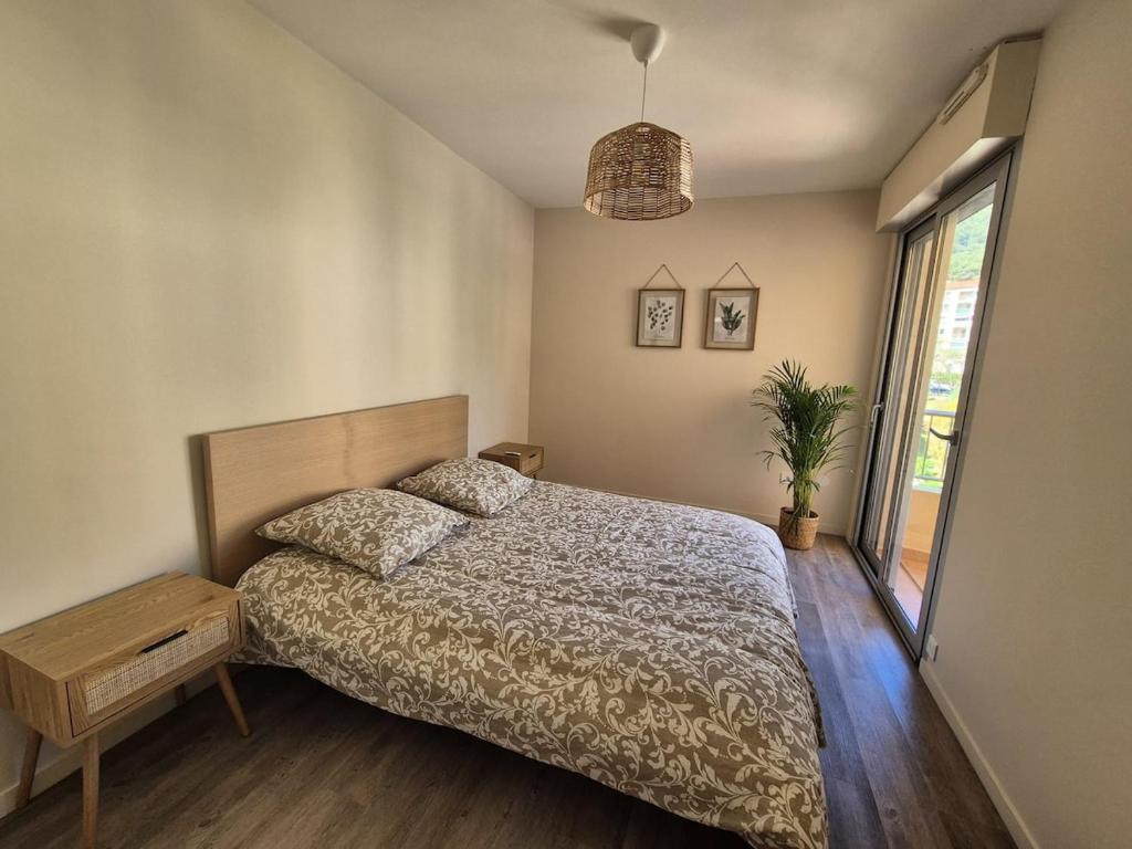 Un dormitorio con una cama y una ventana grande. en Apartment 6 minutes from Monaco train station, en Beausoleil