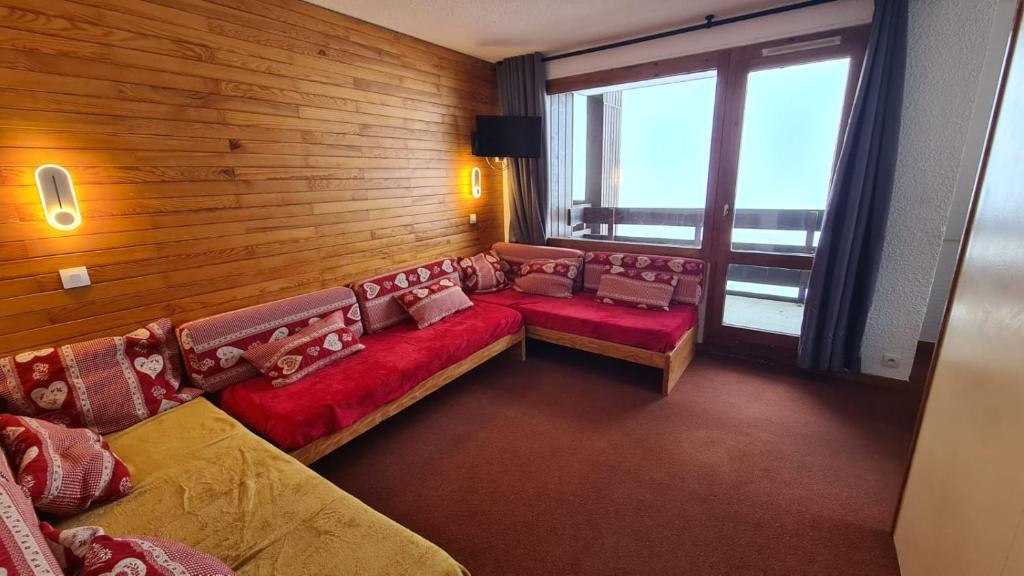 un salon avec des canapés rouges et une grande fenêtre dans l'établissement Belle-Plagne, skis aux pieds, à La Plagne Tarentaise