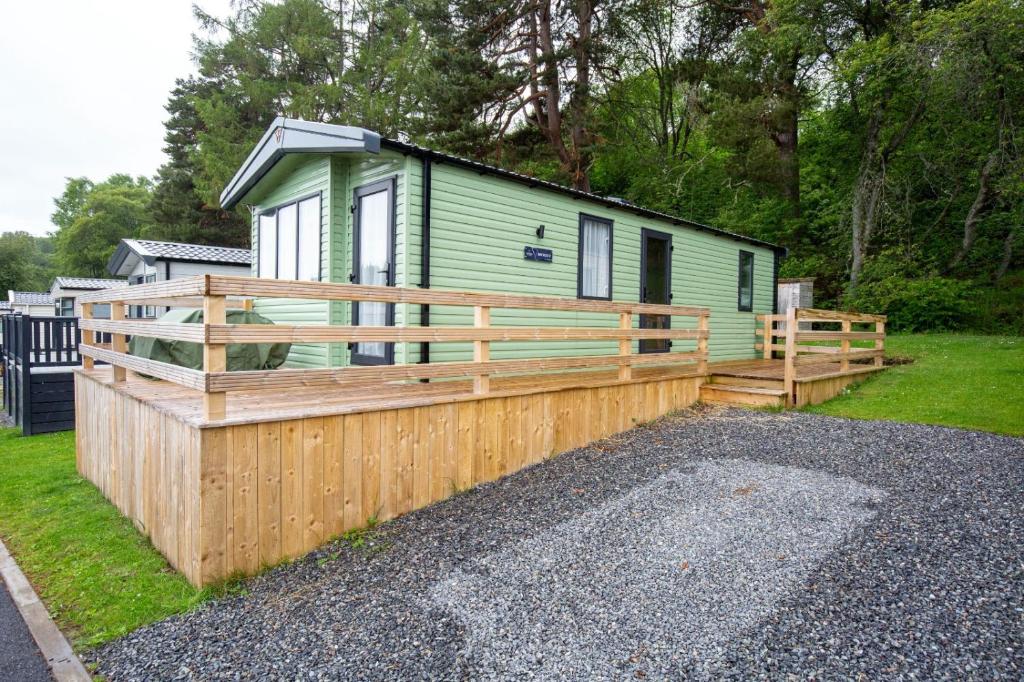 una casa verde con una recinzione di legno intorno di Grantown Getaway - SJA Stays - Modern 2 Bed Static a Grantown on Spey