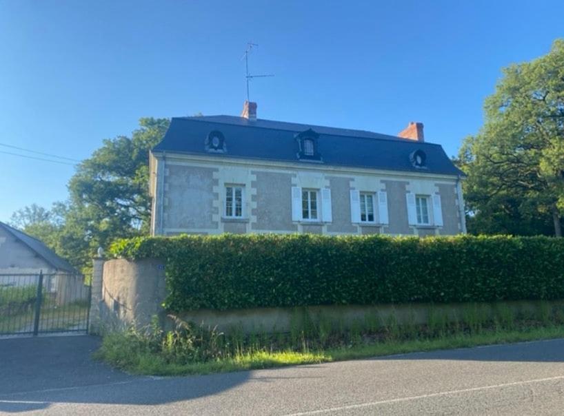 une maison blanche avec une haie devant elle dans l'établissement Appartement, tout confort, à Veigné