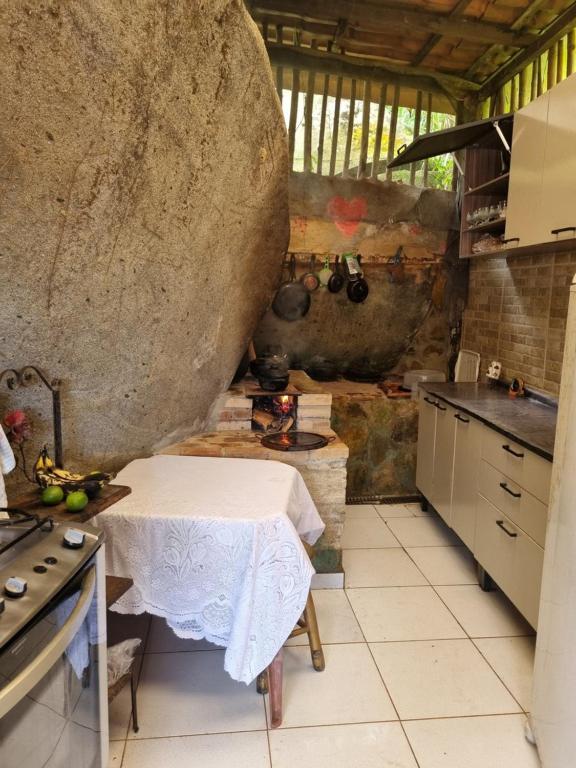 a kitchen with a table and a large rock at Chant of the Birds in Paraty