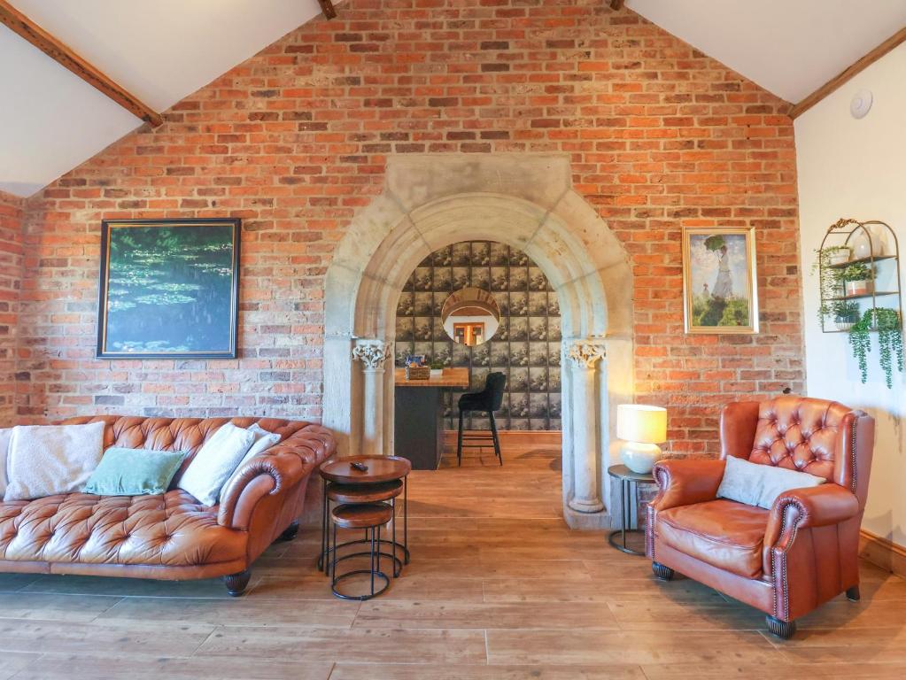 ein Wohnzimmer mit 2 Sofas und einer Ziegelwand in der Unterkunft Molly's Cottage in Malton