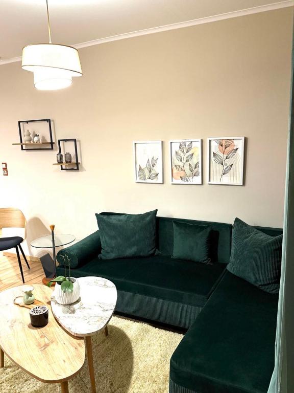 a living room with a green couch and a table at The Little Blooming House in Agíasma