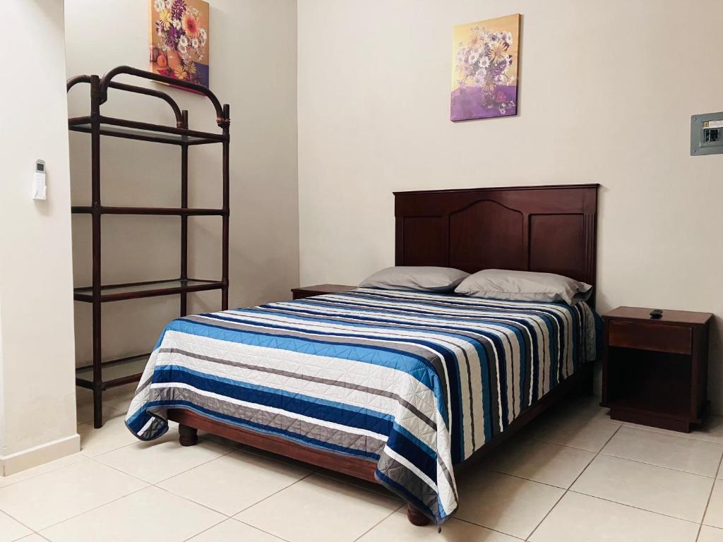 ein Schlafzimmer mit einem Bett mit einer blau-weiß gestreiften Decke in der Unterkunft Casa Mayaka in La Paz