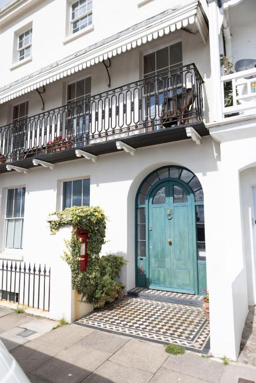 a white house with a blue door and a balcony at Beautiful Beachfront Townhouse in St. Leonards