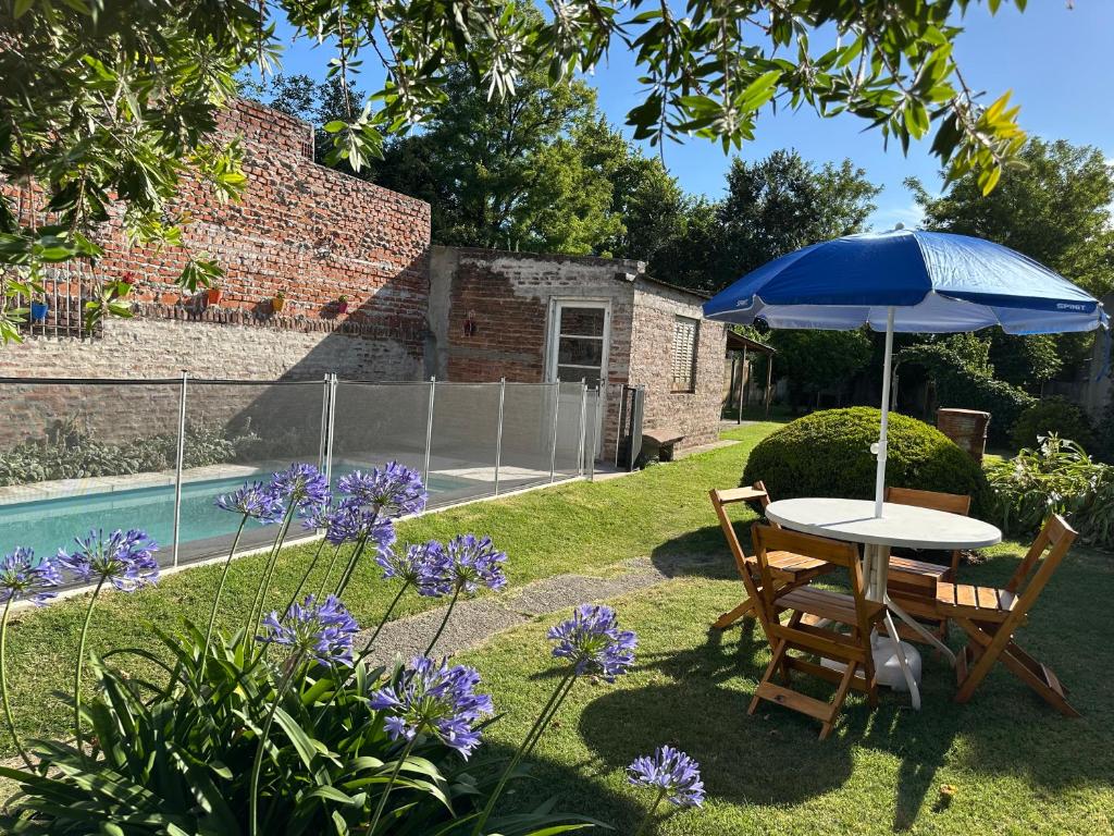 a table and chairs with an umbrella in a garden at Casa Tradicional del Barrio de la Estación in Tandil