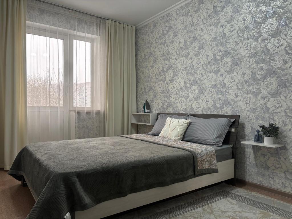 een slaapkamer met een groot bed en een raam bij 2х комнатная квартира в Центре города in Semey