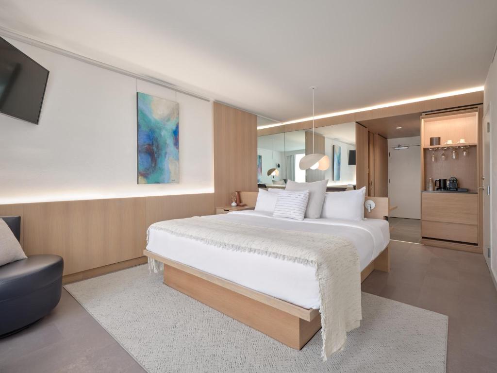 a bedroom with a large white bed and a tv at Hôtel de l'ITHQ in Montréal