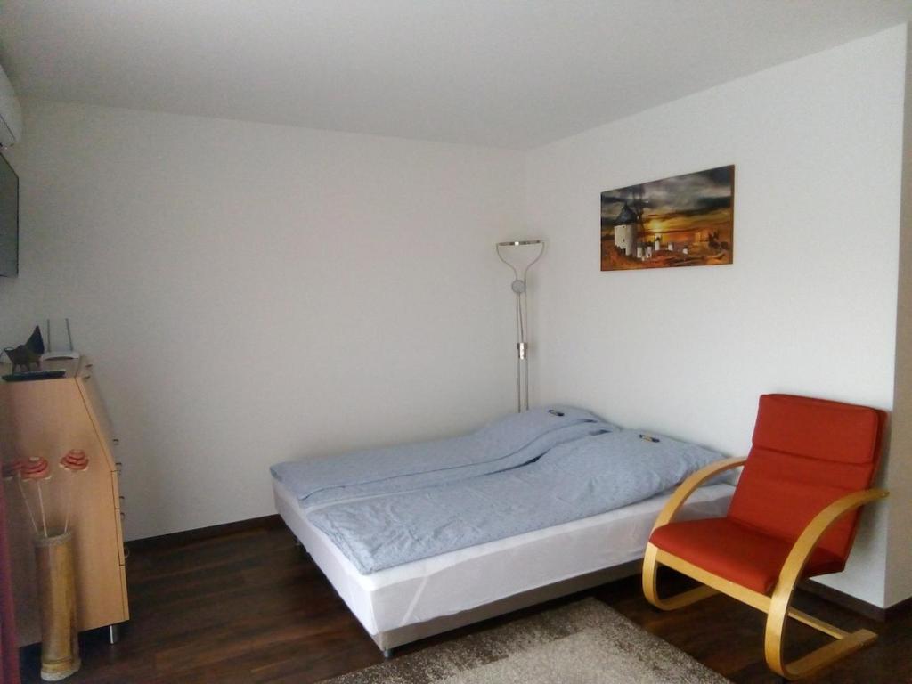 a bedroom with a bed and a red chair at Aquarosa Apartman in Hévíz