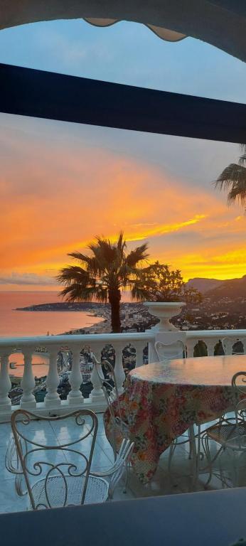 d'une table et de chaises sur un balcon avec vue sur le coucher du soleil. dans l'établissement Olguita, à Menton