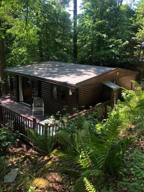 a log cabin in the woods with a deck at Devoke Water in Elterwater