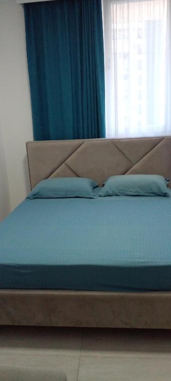 a bed with blue pillows in a bedroom with a window at Royal apartment in Lezhë