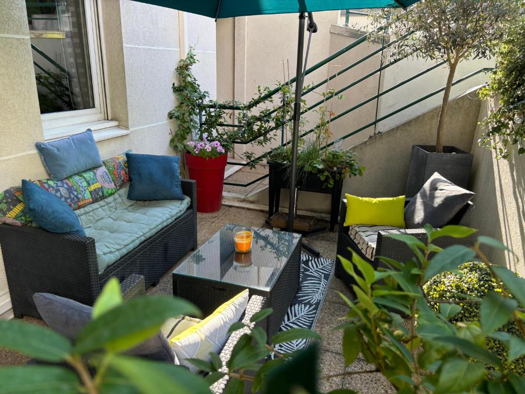 une terrasse avec un canapé, une table et un parasol dans l'établissement Breeze in the city, à Lyon
