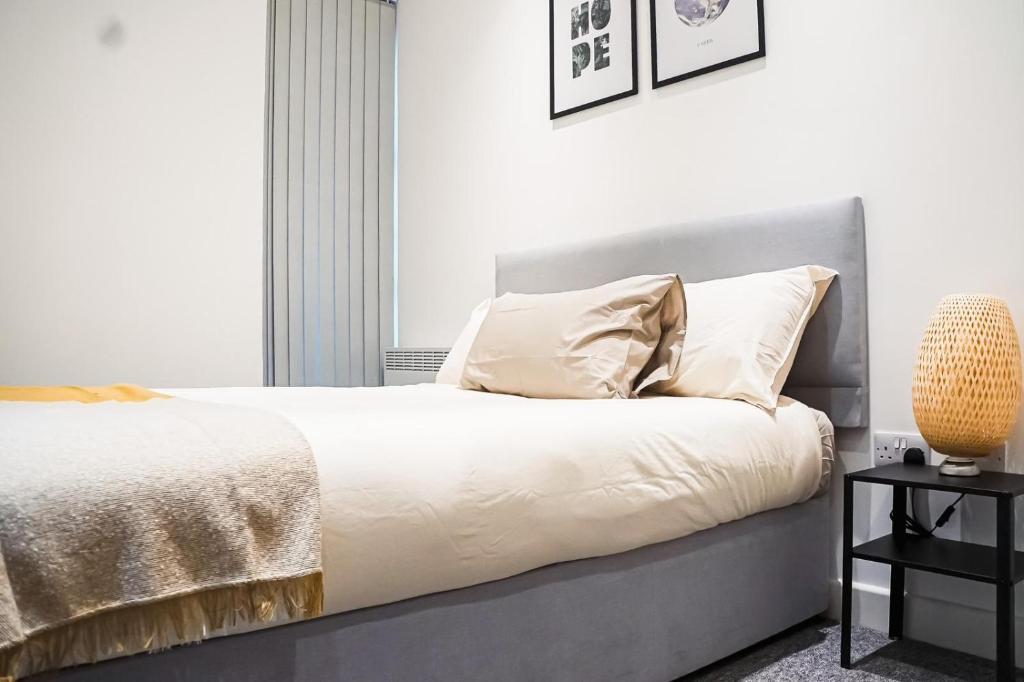 ハウンズローにあるSomerville Apartment London Heathrowの白いシーツと枕が備わったベッドのある寝室