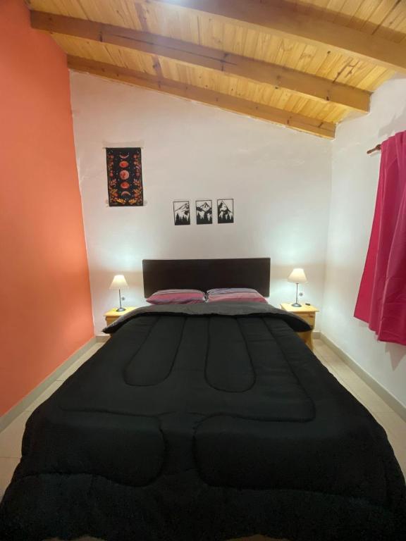 a bedroom with a large black bed in a room at Casitas Del Champaqui in Villa Yacanto