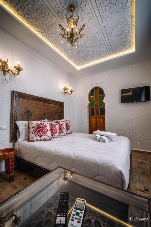 a bedroom with a large bed and a chandelier at Dar Bleumain in Chefchaouen