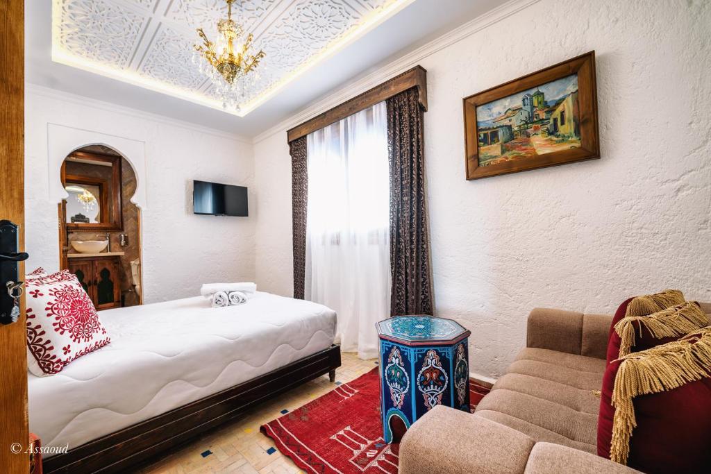 a hotel room with a bed and a couch at Dar Bleumain in Chefchaouen
