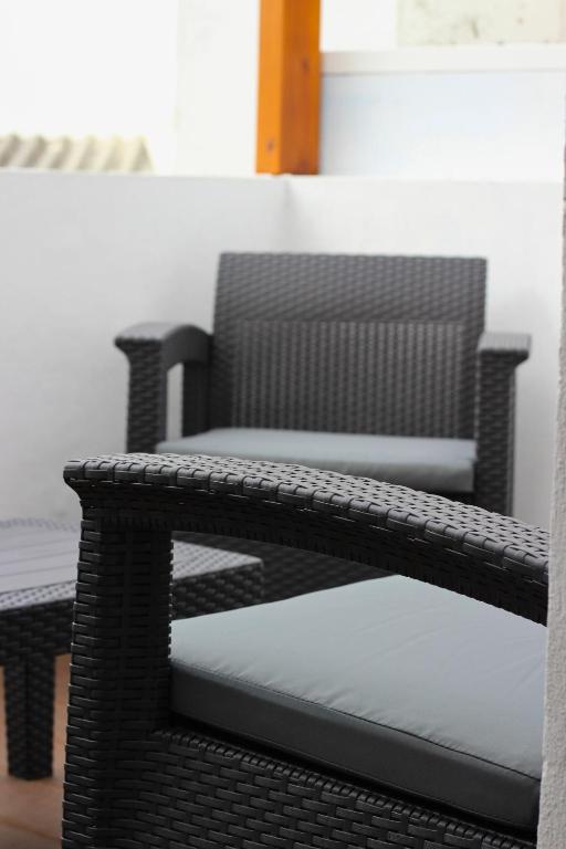 a black wicker chair sitting next to a wall at Casa do Chafariz Velho in Angra do Heroísmo