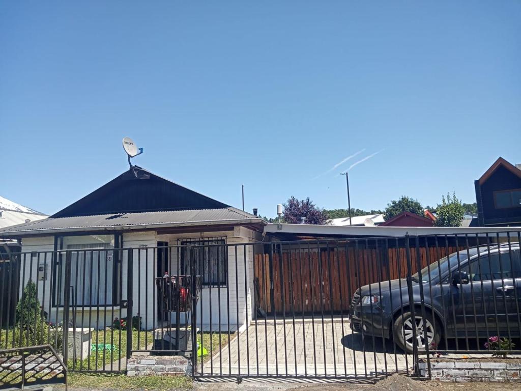 a car parked in front of a house with a fence at Casa Centrica Pucón in Pucón
