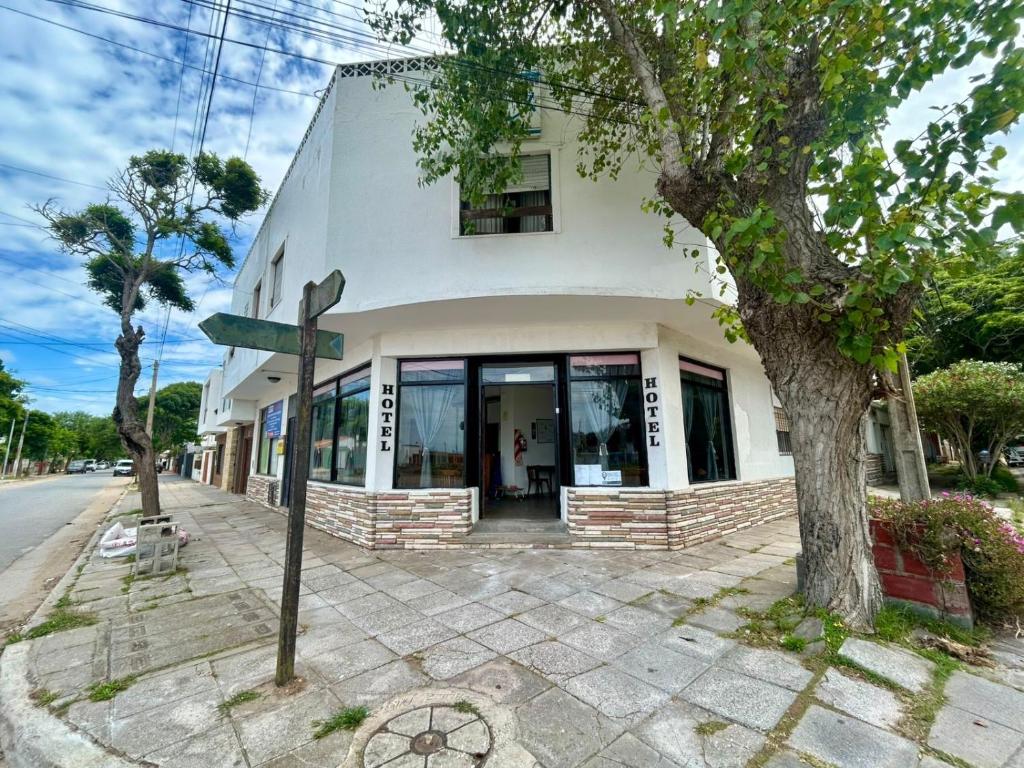 a white building with a tree in front of it at Hotel Zenit in Mar de Ajó