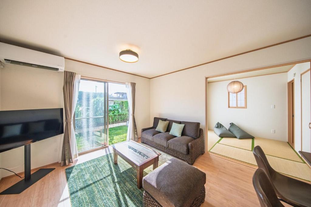 un soggiorno con un divano e una TV di Inamine Terrace K a Nago