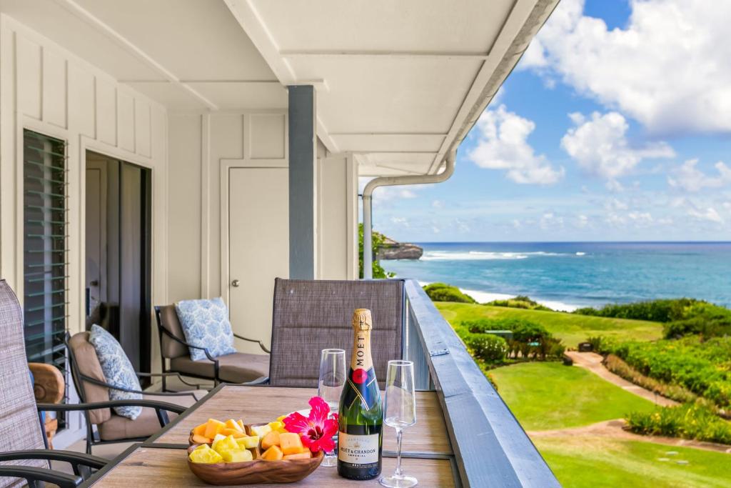 a table with a bottle of wine and a bowl of fruit at Poipu Sands 437: 2BR Ocean View Condo w/ A/C, pool in Koloa
