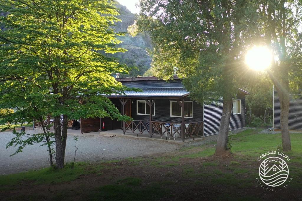 a log cabin in the mountains with a tree at Cabañas Leufu in Futaleufu