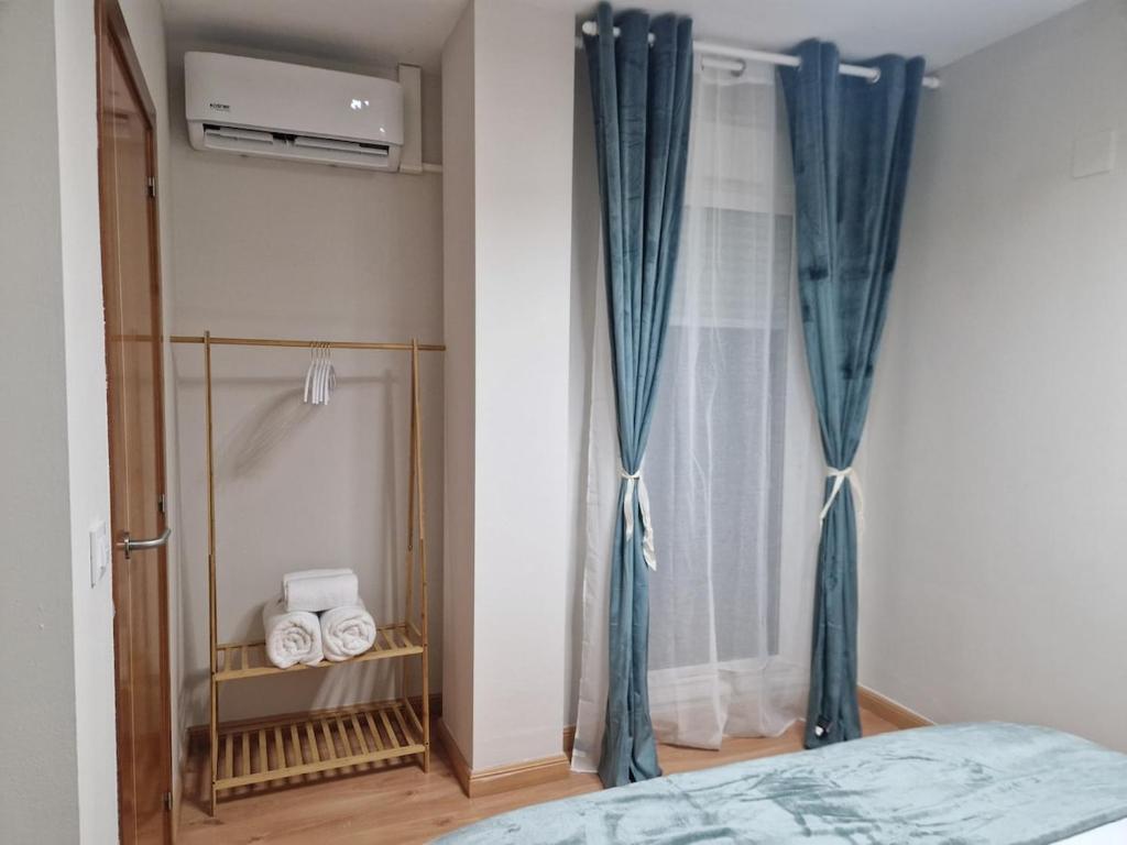 a bedroom with a window with blue curtains at Visita Zaragoza in Zaragoza