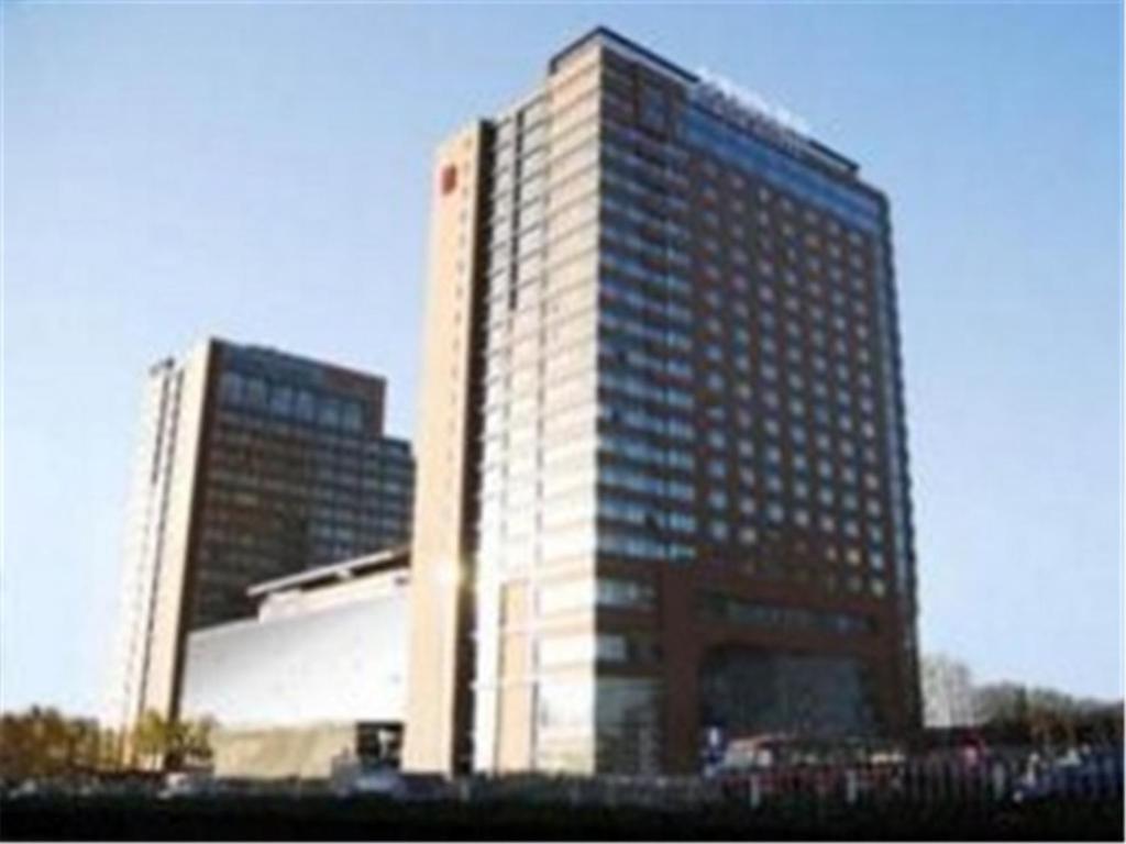 a tall building in front of two other buildings at Wenjin Hotel, Beijing in Beijing