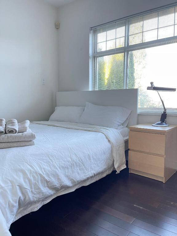 a bedroom with a bed and a lamp on a night stand at Cozy Guest Rooms Near UBC, Downtown and Beaches in Vancouver