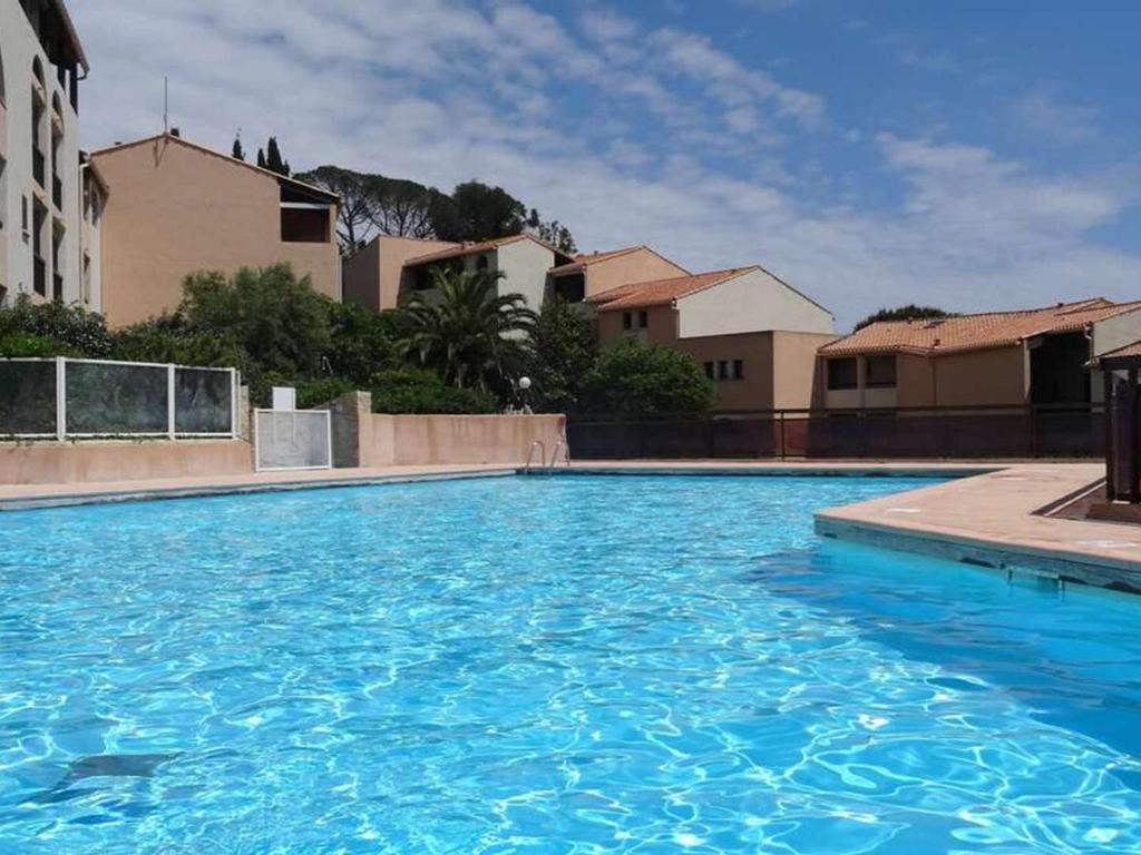 une grande piscine bleue avec des bâtiments en arrière-plan dans l'établissement Confortable T2 Bis aux Issambres avec terrasse et accès piscine et tennis - FR-1-768-109, à Roquebrune-sur Argens
