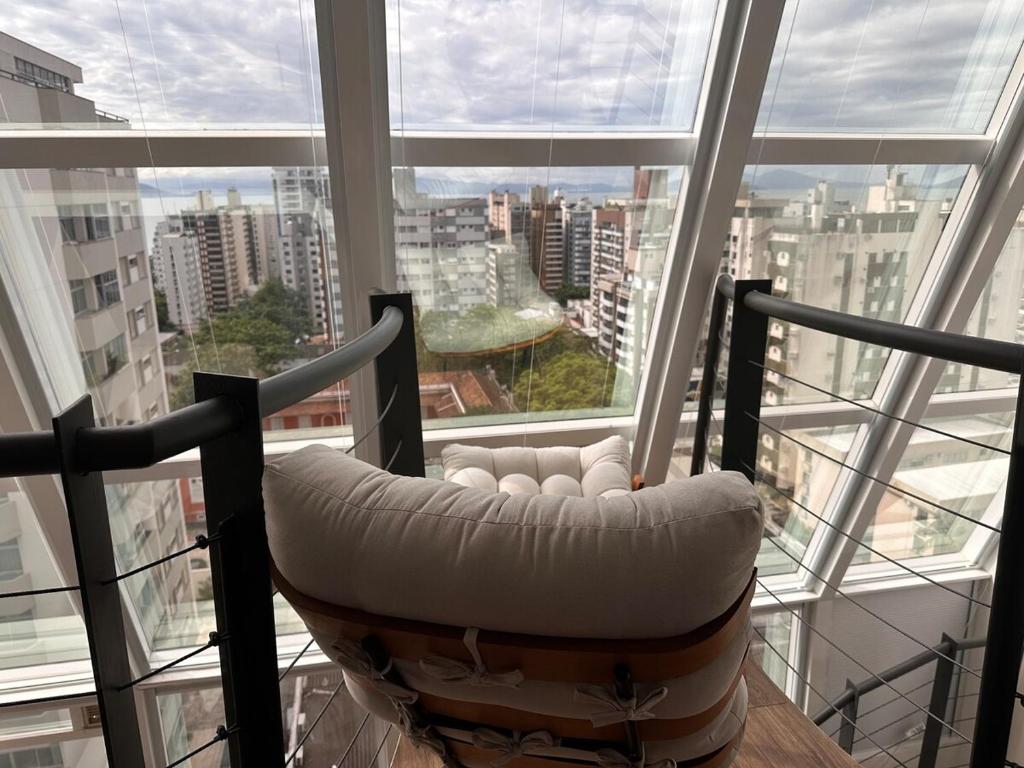 a chair sitting in front of a large window at Loft Duplex com Hidromassagem in Florianópolis