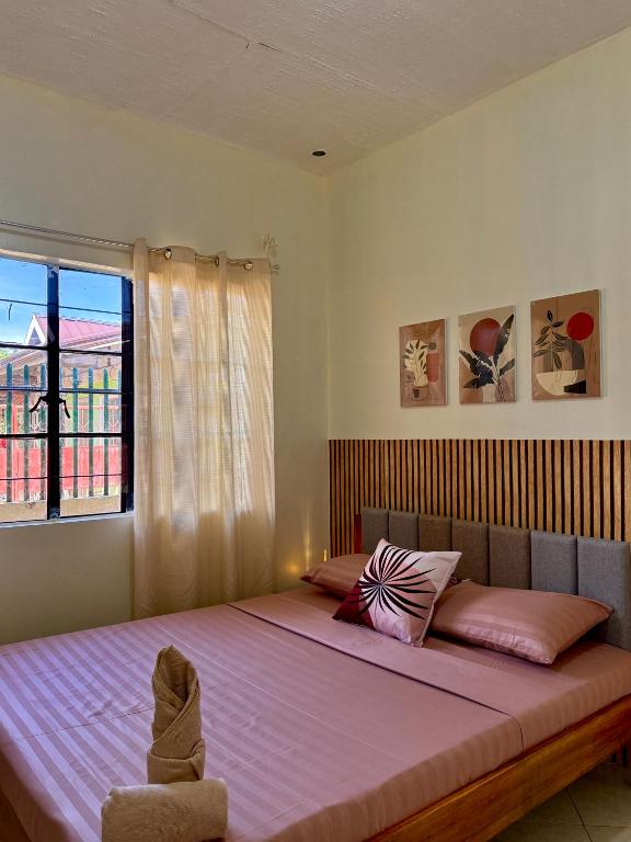 a bedroom with a large bed with pink sheets and a window at AisG Homestay Tres -Fully Furnished Shared Homestay FREE NETFLIX-3mins to Airport in Puerto Princesa City